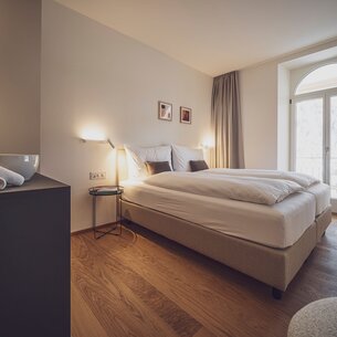 Zimmer mit Doppelbett, Holzboden und Nachttischlampen  | © Davos Klosters Mountains 